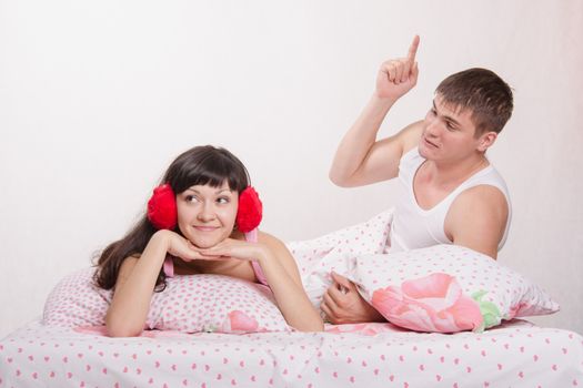 Young family couple quarrels in a bed