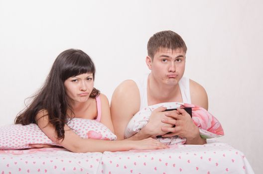 Young beautiful couple watching a movie in the tablet computer while lying in bed