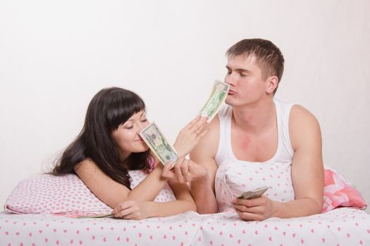 Young couple with money lying in bed