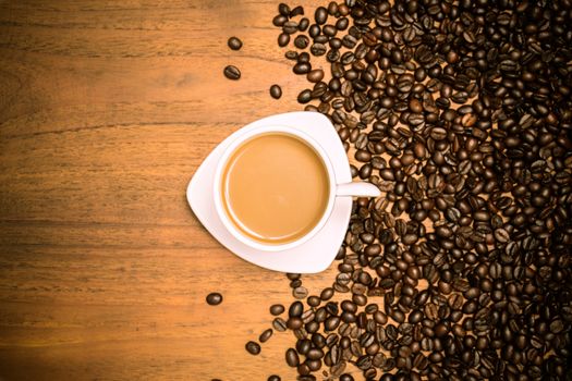 Coffee cup and coffee beans on teak wooden table, vintage