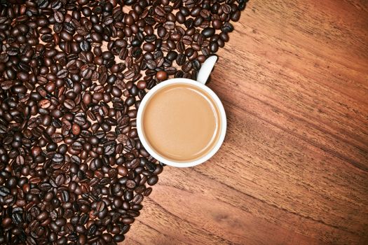 Coffee cup and coffee beans on teak wooden table, vintage