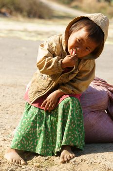 BUON ME THUOT, VIET NAM- FEB 7:Unidentified Asian children sitting on pavement, Vietnamese kid hungry and eating, dirty clothing, barefoot, poverty child at poor countryside, Vietnam, Feb 7, 2014