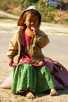 BUON ME THUOT, VIET NAM- FEB 7:Unidentified Asian children sitting on pavement, Vietnamese kid hungry and eating, dirty clothing, barefoot, poverty child at poor countryside, Vietnam, Feb 7, 2014