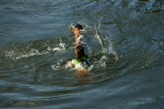 KHANH HOA, VIET NAM- FEB 5: Lifestyle of Vietnamese country children, group of Asian girl bath on river, they swim, splash water, laugh with friend in summer, Vietnam, Feb 5, 2013