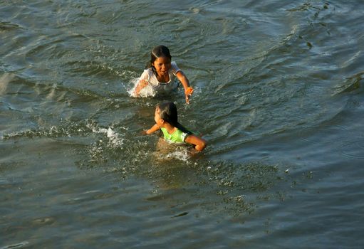 KHANH HOA, VIET NAM- FEB 5: Lifestyle of Vietnamese country children, group of Asian girl bath on river, they swim, splash water, laugh with friend in summer, Vietnam, Feb 5, 2013