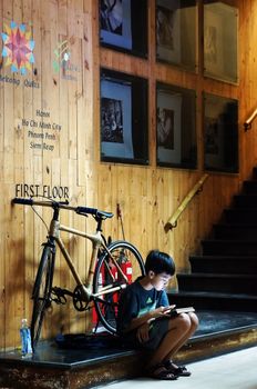 HO CHI MINH CITY, VIET NAM- OCT 12: Unidentified Asian children sitting at staircase of house with tablet, Vietnamese kid looking with high concentration, modern technology, Vietnam, Oct 12, 2014