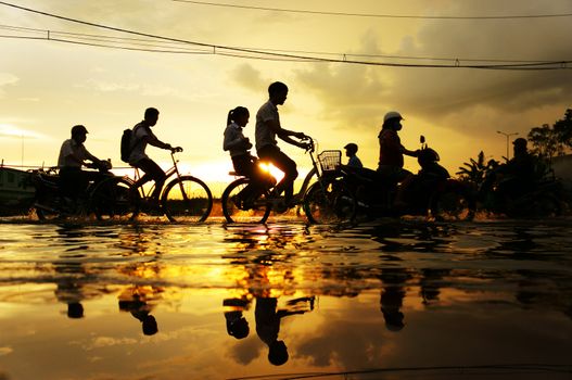 HO CHI MINH CITY, VIET NAM- OCT 9: Amazing scene of Ho Chi Minh city when flood tide, street flooded, silhouette of people riding motorbike, bike in water at sunset, yellow sun, Vietnam, Oct 9, 2014