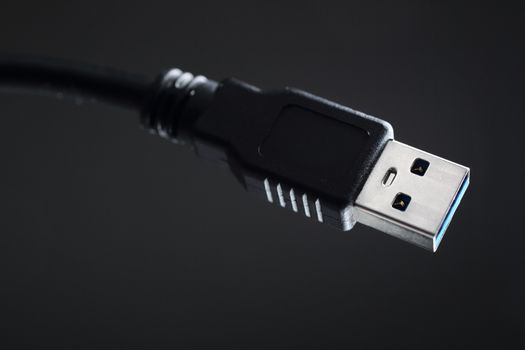 Close-up black USB cable on gray background.