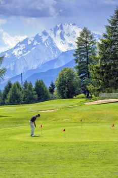 Crans-Montana, Switzerland, May 28, 2012 : man playing golf in front of Alps mountain
