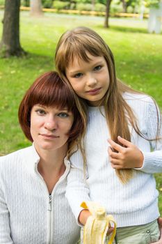 Photo of mother and daughter eating banana