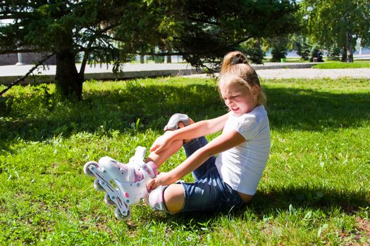Cute girl put on roller skates in summer
