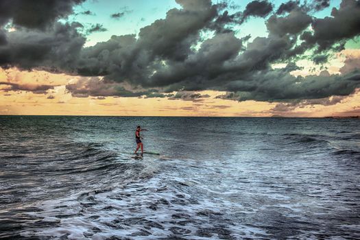 man on a surf board slowly landing under clouds