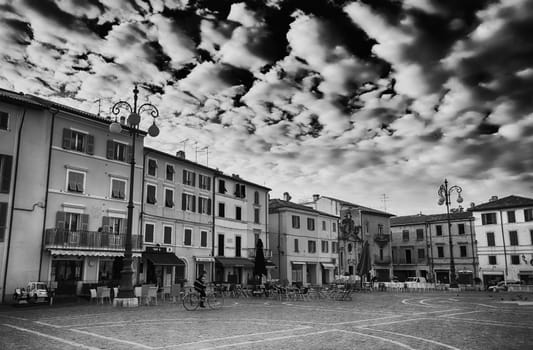 a biker pedals through a central square in a small italian town early in the morning