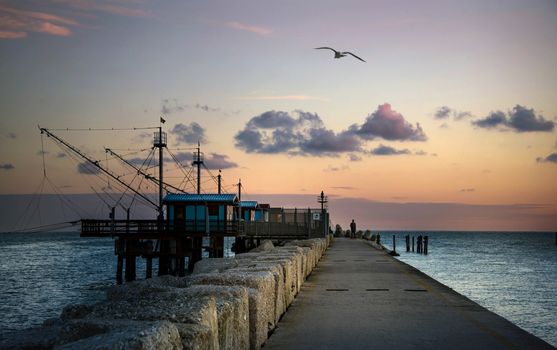 melancholic morning at pier with a man staring at the horizon beside fishermen huts