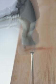 blurred image of nail being hammered into plank
