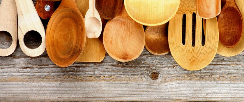 Border of Various Wooden Spoons and Cooking Utensils isolated on Rustic Wooden background. Horizontal View