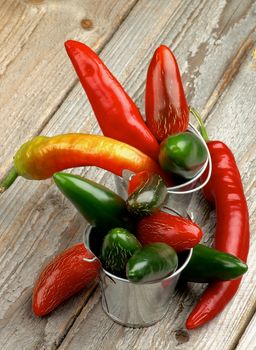 Arrangement of Red and Green Habanero and Jalapeno Chili Peppers in Tin Buckets on Rustic Wooden background 