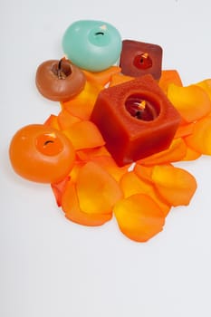 Spilt petals of the orange-rose around the aromatic candle