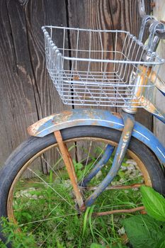 Vintage bike displayed against a wooden fence outside.