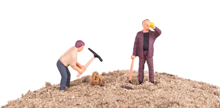 Miniature workers with pickaxes on a mountain of sand