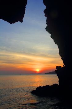 View on beautiful sunset above the sea through rock silhouette