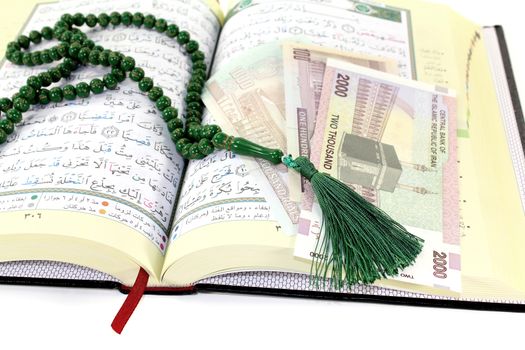 whipped Quran with Iranian Rials before light background