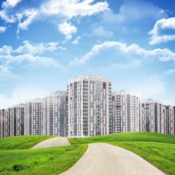 Tall buildings, green hills and road against sky with clouds. Architectural concept