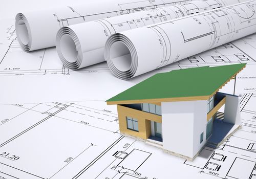 Small model house with green roof near scrolls of architectural drawings. Construction concept