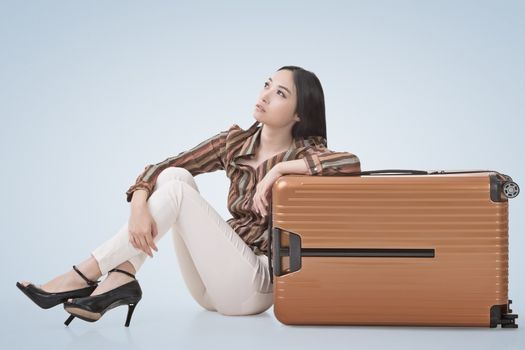 Modern Asian woman sit on ground with a luggage.