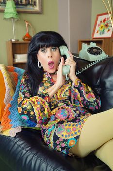 Startled woman in paisley dress covering telephone