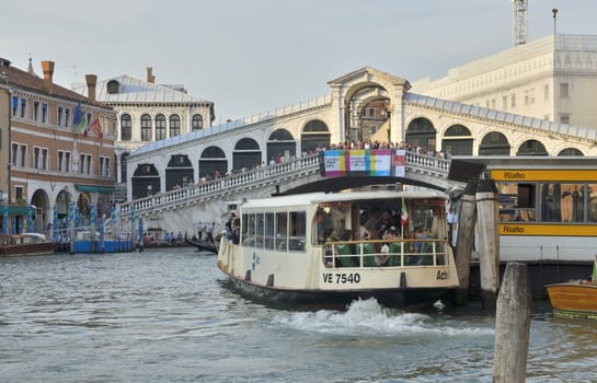 Tourists on the Rialto Bridge, one of the four bridges spanning the Grand Canal in Venice, Italy. It is the oldest bridge across the canal.