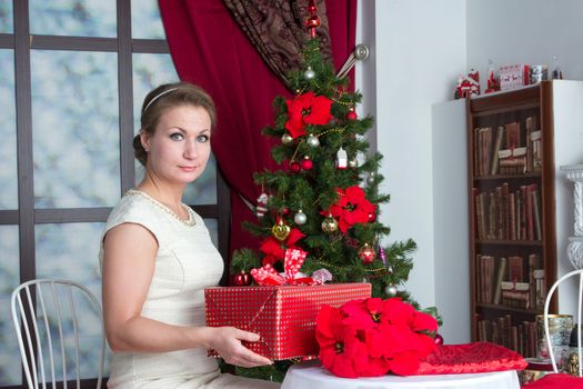 Happy adult Woman with gift box under tree at home