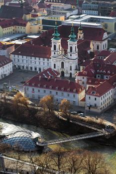 Graz, Austria - January 16, 2011: The Mariahilfer church and Island on Mur river connected by a modern steel and glass bridge, Styria, Graz, Austria
