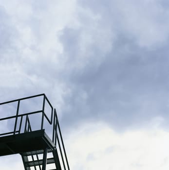 Dark metal staircase and cloudy sky