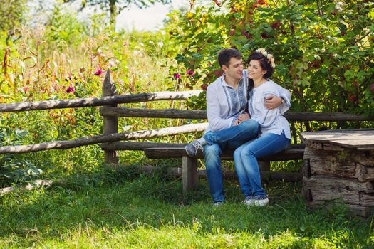 Lovely couple in Ukrainian style clothing sitting on bench and flirting