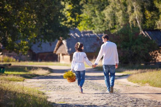 Young couple in Ukrainian style clothing walking along the road