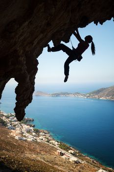 Silhouette of a young female rock climber on a cliff. Kalymnos Island, Greece