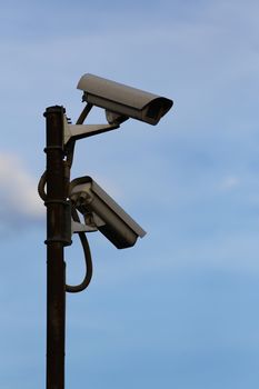 Two surveillance cameras against the sky