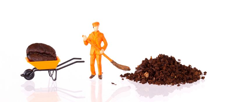 Miniature worker with broom working on a grinded coffee bean