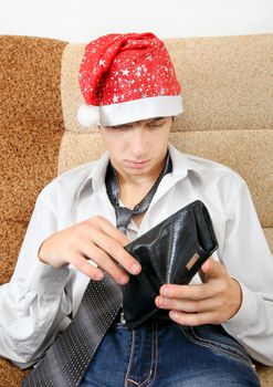 Teenager in Santa Hat Checking Empty Wallet on the Sofa at the Home