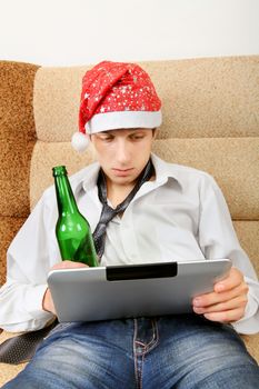 Tired Teenager in Santa Hat with Tablet Computer and Bottle of the Beer