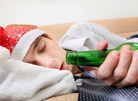 Drunken Teenager sleeping in Santa Hat and Bottle of the Beer on the Sofa