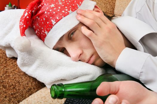 Sad and Tired Teenager with Bottle of the Beer and Santa Hat on the Sofa at the Home