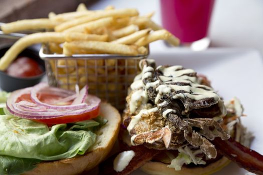 Fried soft shell crab sandwich with red onion, lettuce, and tomato accompanied by french fries is delicious and colorful