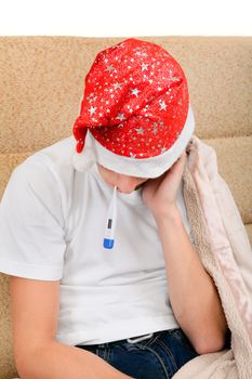 Sick Teenager in Santa Hat with Thermometer on the Sofa at the Home