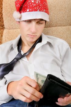 Teenager in Santa Hat Checking the Wallet on the Sofa at the Home