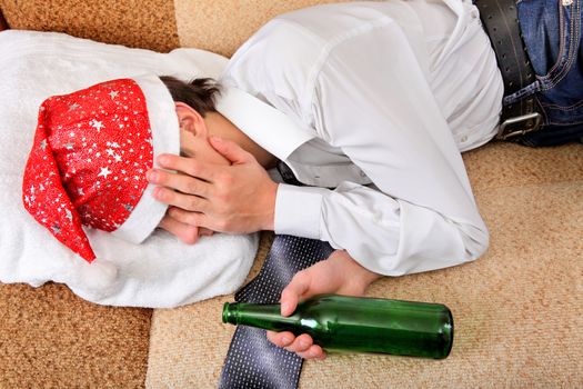 Drunken Teenager sleeping in Santa Hat and Bottle of the Beer on the Sofa