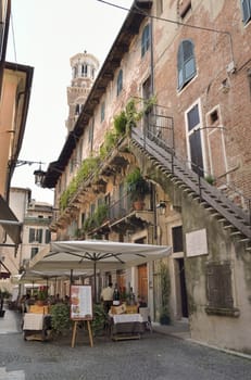 Outdoor restaurant  in a narrow street of Verona, Italy. The city has been awarded World Heritage Site status by UNESCO because of its urban structure and architecture.
