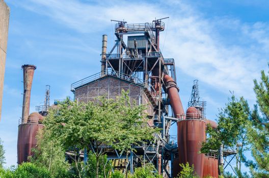 Old rusty abandoned blast furnace plant against a blue sky