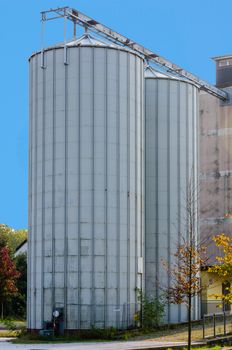 Loading station, two silver silos for feed at a railway station.